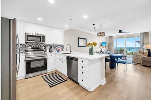 Une cuisine moderne avec des meubles blancs, des appareils en acier inoxydable et un grand îlot central.