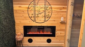 A wooden wall with a fireplace, a decorative metal piece, and a small table.