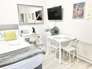 Ein modernes Hotelzimmer mit einem Bett, einem Schreibtisch, einem Sessel, einem Fernseher und einer Heizung.