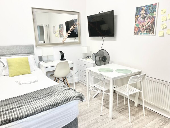 Een moderne hotelkamer met een bed, een bureau, een stoel, een televisie en een radiator.