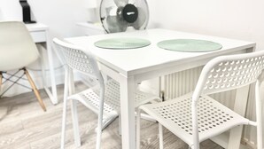 A white dining table with two green placemats, white chairs, and a white radiator. - Flat 2  (London)