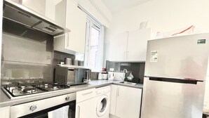 A modern kitchen with stainless steel appliances, a built-in oven, a washing machine, and a refrigerator. - Flat 2  (London)