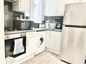Eine moderne Küche mit Edelstahlgeräten, inklusive Backofen, Mikrowelle und Geschirrspüler, sowie ein Fenster für natürliches Licht.