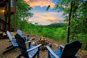 A wooden deck with Adirondack chairs and a fire pit, overlooking a forested landscape. - 10% Off Member Deal•OMG Views•5min>Hochatown•Hot Tub•Firepit•Deck•King Bed (Broken Bow)