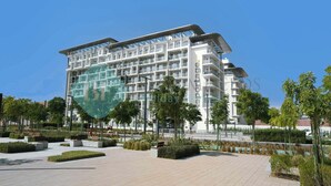 A modern multi-story hotel with a flat roof, balconies, and a landscaped courtyard with benches and greenery. - Bloomfields Elegant STU in Oasis Masdar (Abu Dhabi)