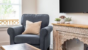 Una sala de estar moderna con un sillón gris oscuro, una mesa de centro de madera y una chimenea decorativa.