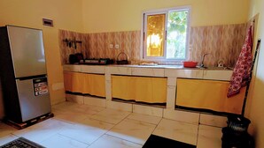 A compact kitchen with a refrigerator, a window, and a sink. - Red Villa on Lionsrest - a tropical garden 500m from the Atlantic beach (Grand Bassam)