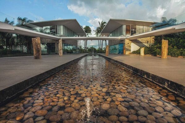 A modern building with a central water feature and a stone pathway.