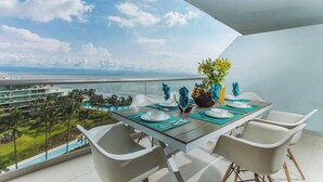 A dining area with a table set for four, overlooking a pool and ocean view. - Peninsula Apartment 8-Best View - 3 Bedrooms (Bucerías)