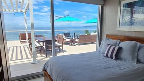 A bedroom with a large bed, a view of the beach, and a patio area with outdoor furniture. - Penthouse in front of Peninsula Nuevo Vallarta Beach. (Bucerías)