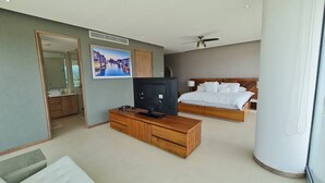 A modern hotel room with a bed, a TV, a wooden console, a ceiling fan, and a large window. - Penthouse in front of Peninsula Nuevo Vallarta Beach. (Bucerías)