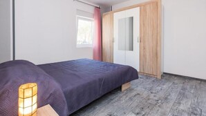 A bedroom with a bed, a wardrobe, a window with curtains, and a bedside lamp. - Modern Apartments in Zadar with Private Terrace - Studio Apartment with Terrace (Zadar)