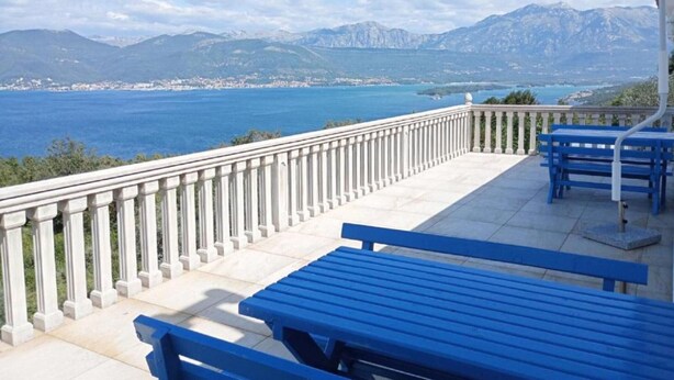 A terrace with a view of a coastal landscape, featuring mountains and a body of water.
