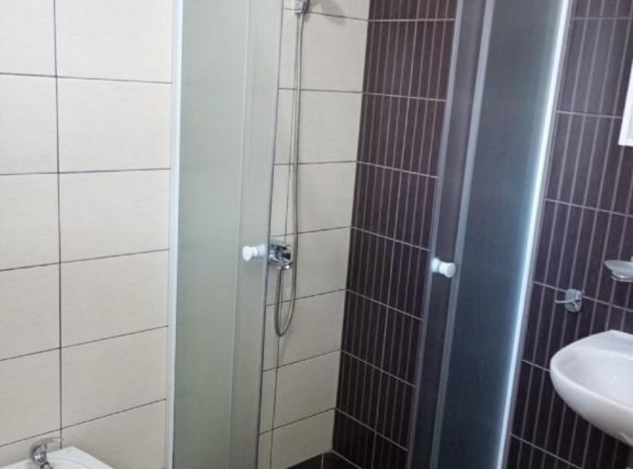 A bathroom with a shower, a sink, and tiled walls.
