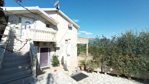 A two-story building with a balcony, satellite dish, and a stone-paved courtyard.