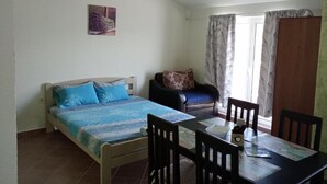 A bedroom with a bed, a chair, a table, and a window with curtains.