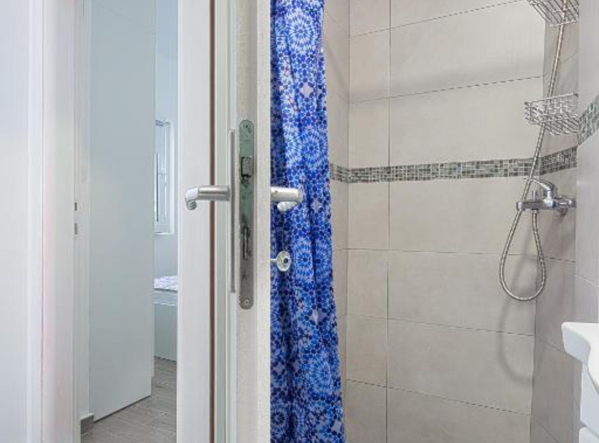 Een badkamer met een douche, een decoratief gordijn en een betegelde muur.