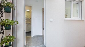 Une porte qui donne sur une cuisine équipée de placards et d’une fenêtre.