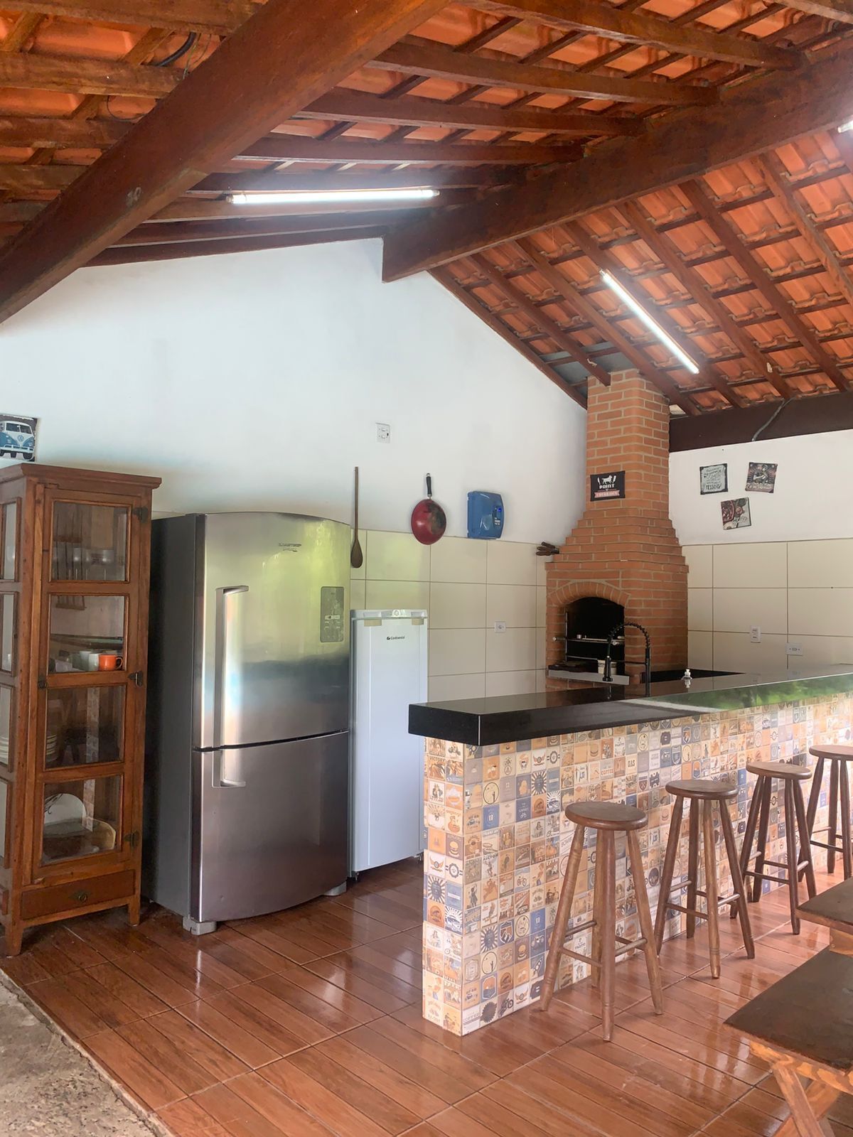 Une cuisine avec un plafond en bois, un réfrigérateur, un lave-vaisselle et un four en briques.