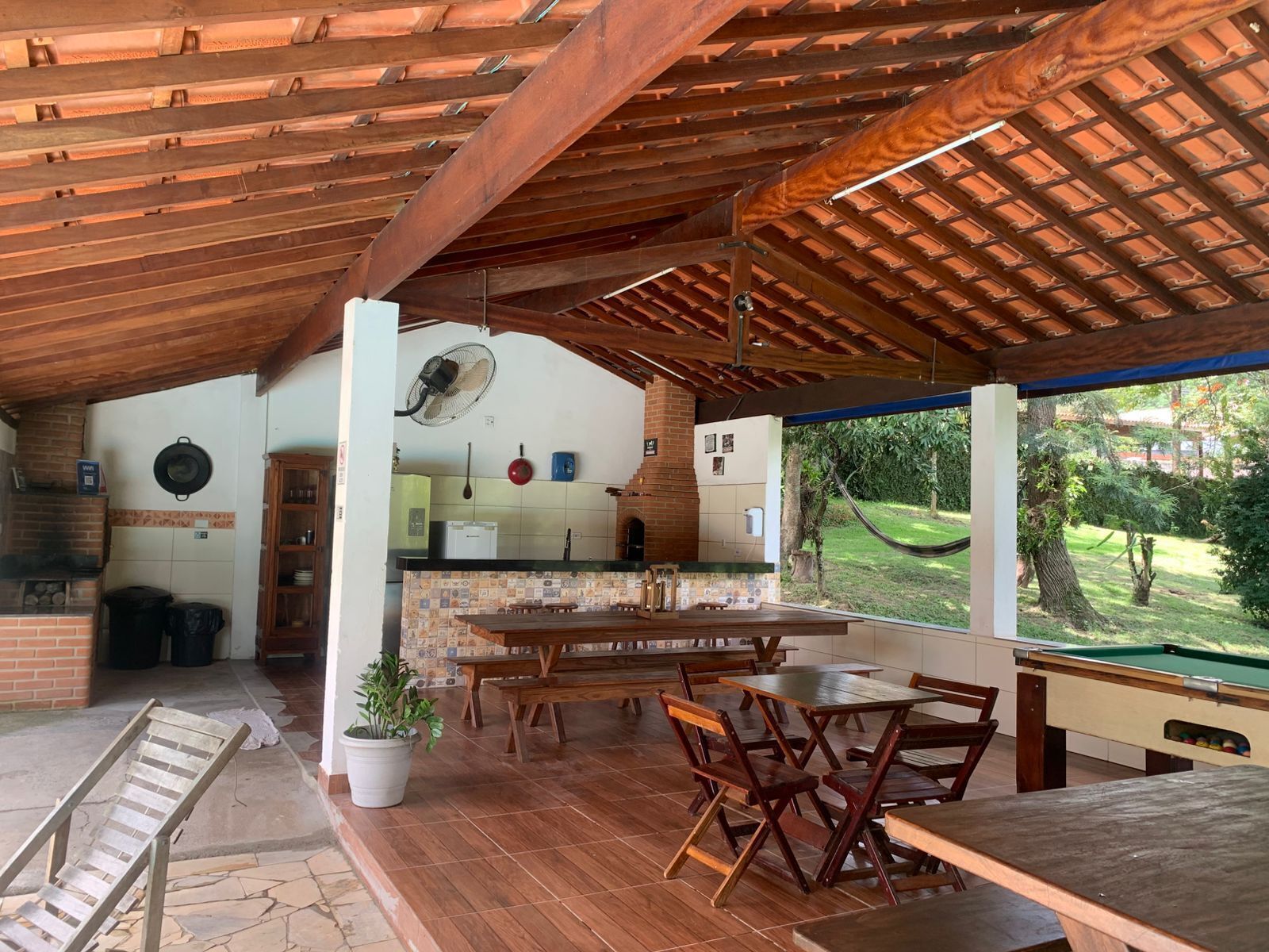Une cuisine ouverte avec des poutres en bois, un coin repas avec des bancs et une vue sur un jardin.