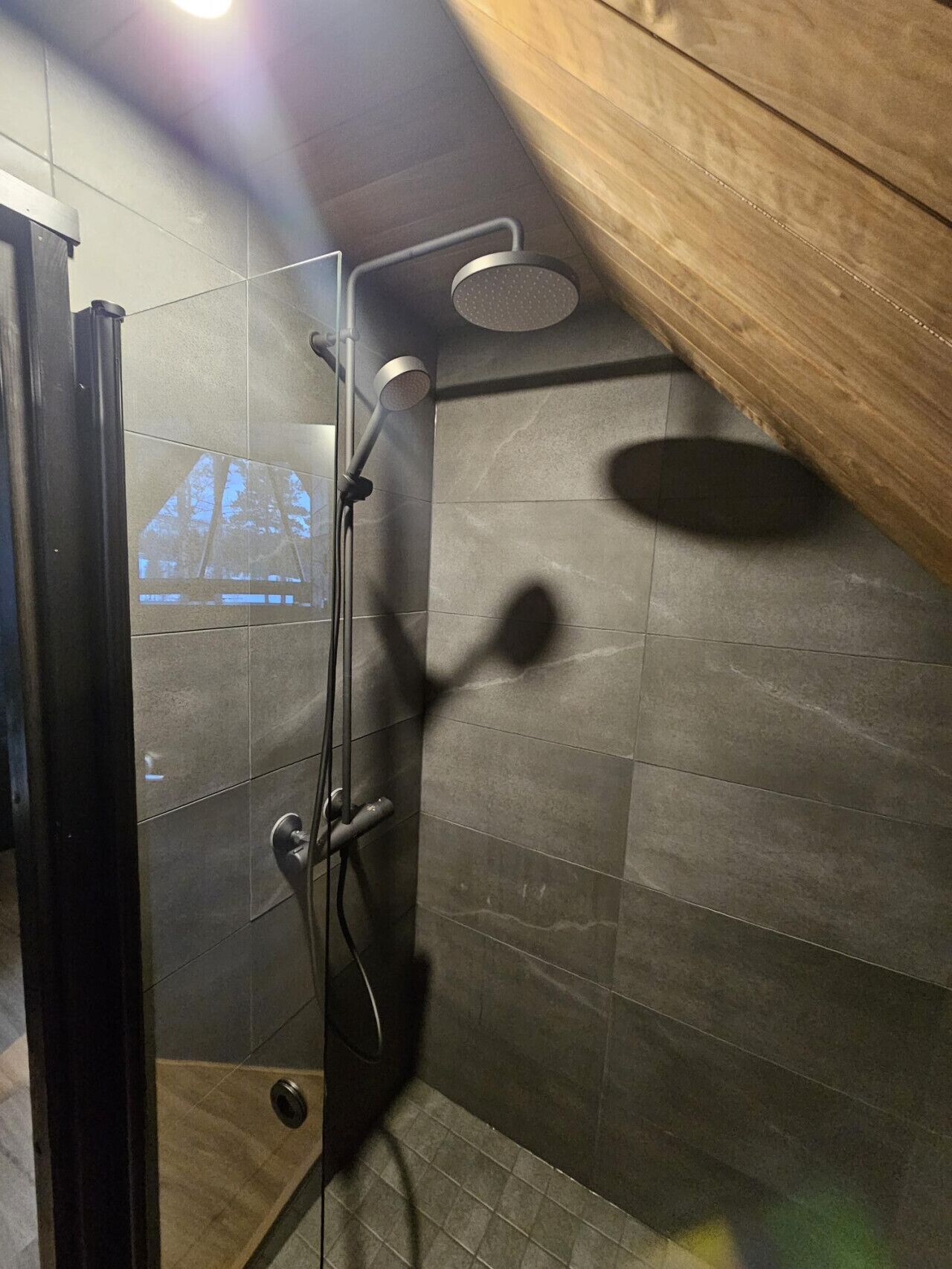 A modern shower with a glass door, a handheld showerhead, and a wall-mounted showerhead.