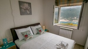 Ein Schlafzimmer mit Bett, Nachttisch, Fenster und Blick sowie Radiator.