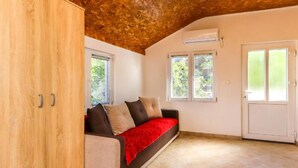 Una stanza accogliente con soffitto in legno, un divano con una coperta rossa e una porta bianca.
