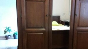 Eine Holztür, die in ein Schlafzimmer mit Bett und Schreibtisch führt.