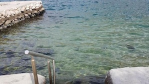Ein klares Schwimmbecken mit Stufen, umgeben von Steinmauern.
