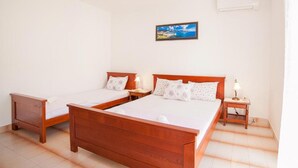 Habitación de hotel con dos camas de madera, una mesita de noche, una lámpara y un cuadro en la pared.