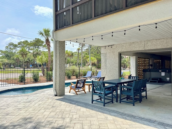 An outdoor patio with a pool, lounge chairs, and a dining area.