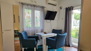 A small room with a table and two chairs, a TV mounted on the wall, and a sliding door leading to a balcony. - Chic & Sleek Apartments in Kotor - Studio Apartment Ground Floor (Kotor)