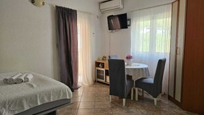 A room with a bed, a desk with two chairs, a TV, and a wardrobe. - Chic & Sleek Apartments in Kotor - Studio Apartment with Balcony (Kotor)
