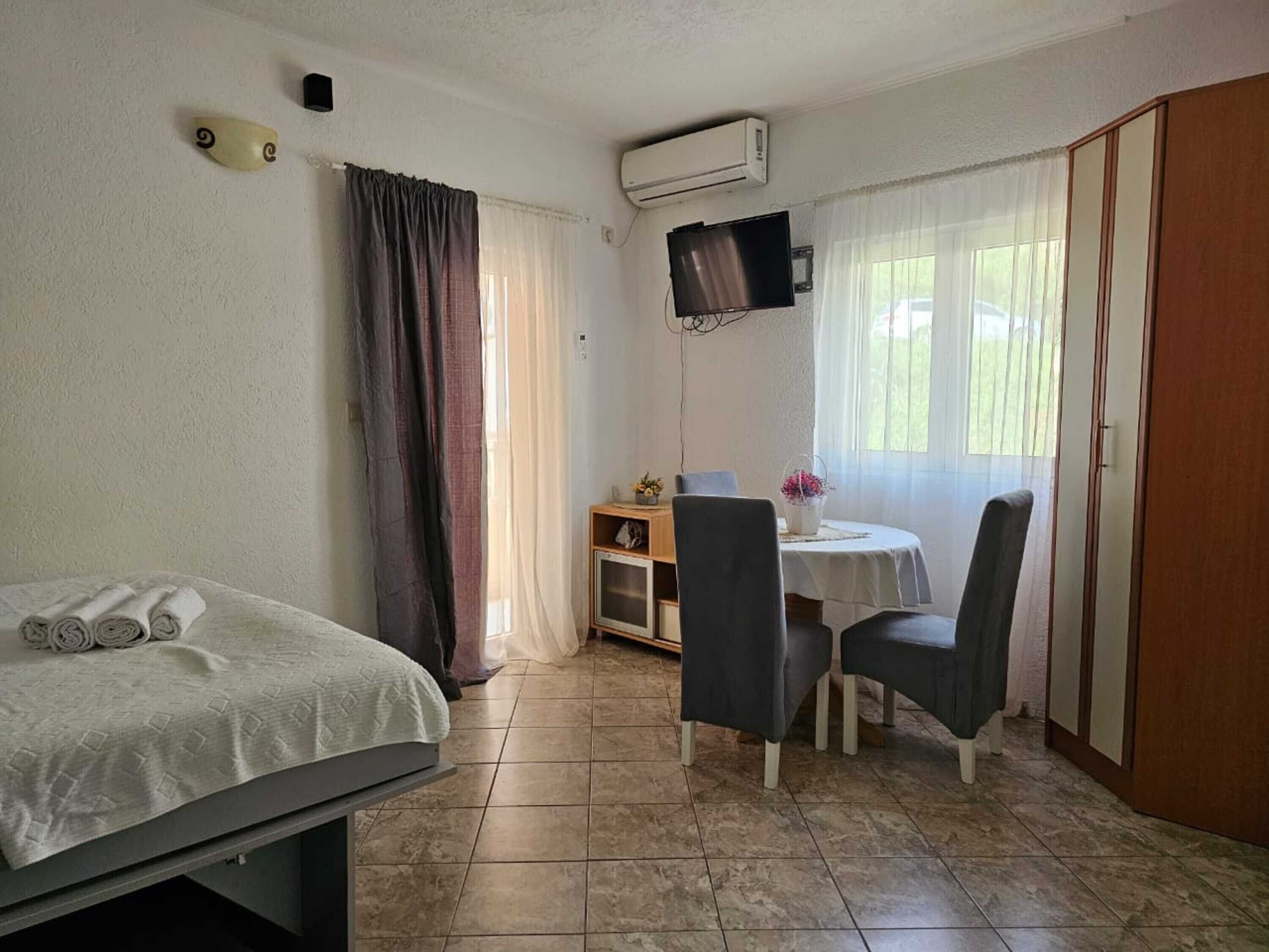 A room with a bed, a desk with two chairs, a TV, and a wardrobe.
