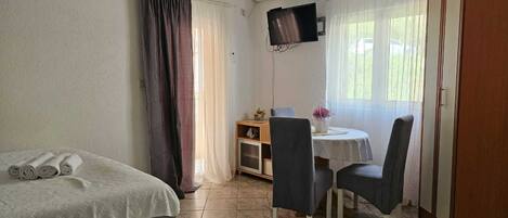 A room with a bed, a desk with two chairs, a TV, and a wardrobe.