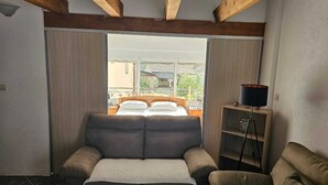 A bedroom with a large bed, a sofa, and a small table with a lamp.