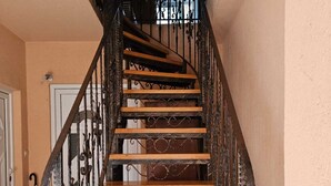 A wooden staircase with ornate metal railings and a handrail, leading to an upper floor.