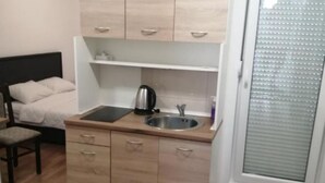 Une petite cuisine équipée comprenant un lit, une chaise et une petite table.