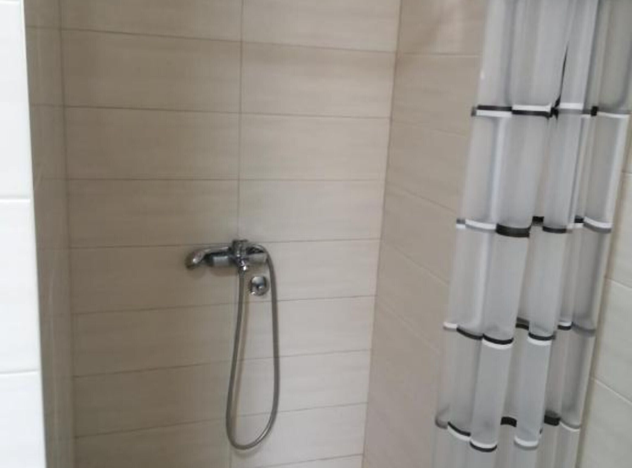 A shower with a handheld showerhead and a vertical rain showerhead.