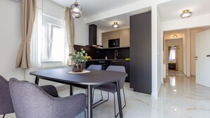 A modern kitchen with dark cabinets, a black microwave, and a stainless steel sink. - Two Bedroom Apartment with Balcony (Zadar)