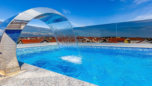 Uma piscina com água azul cristalina e estrutura de vidro singular.