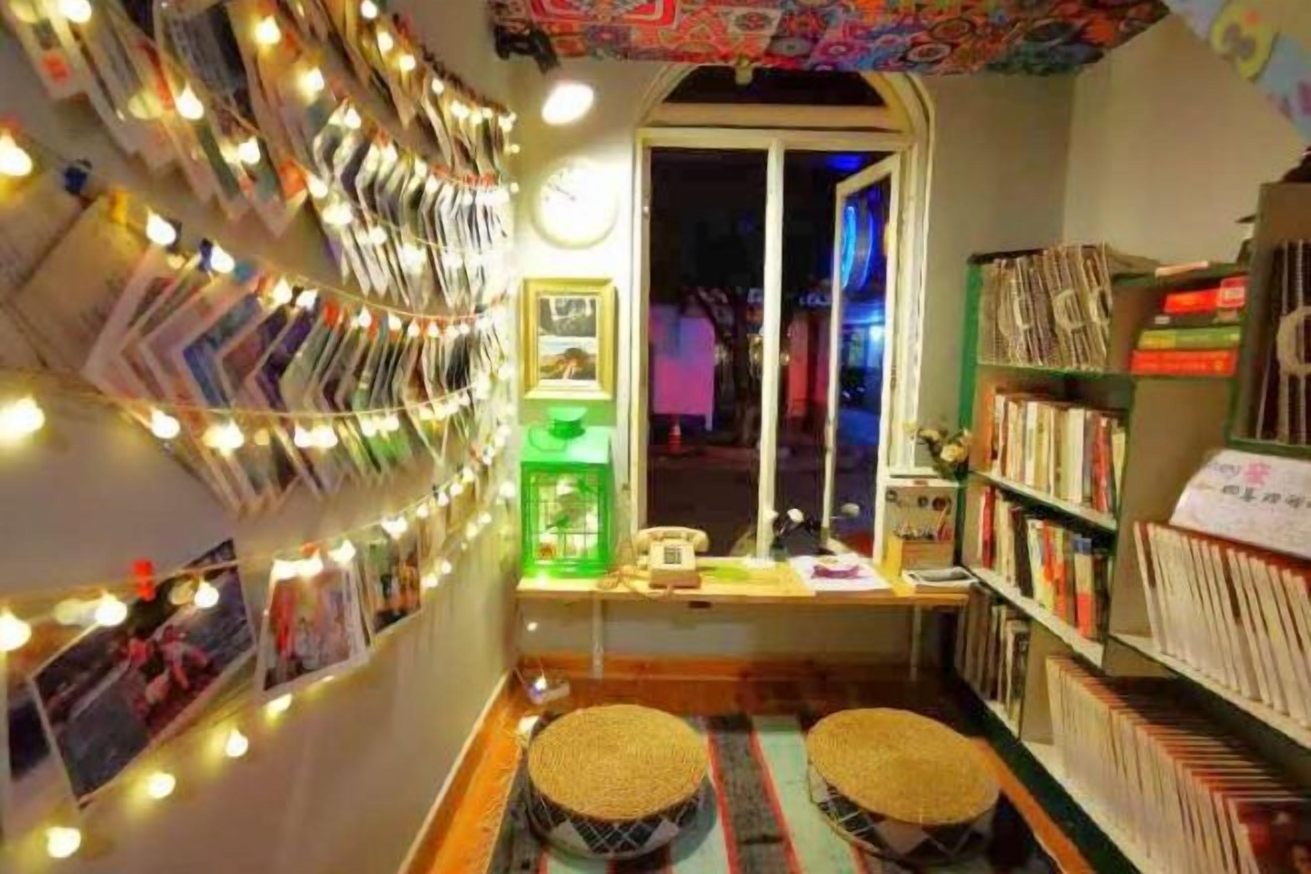 A cozy reading nook with a wall of books, a small table with a lamp, and a window with a view.