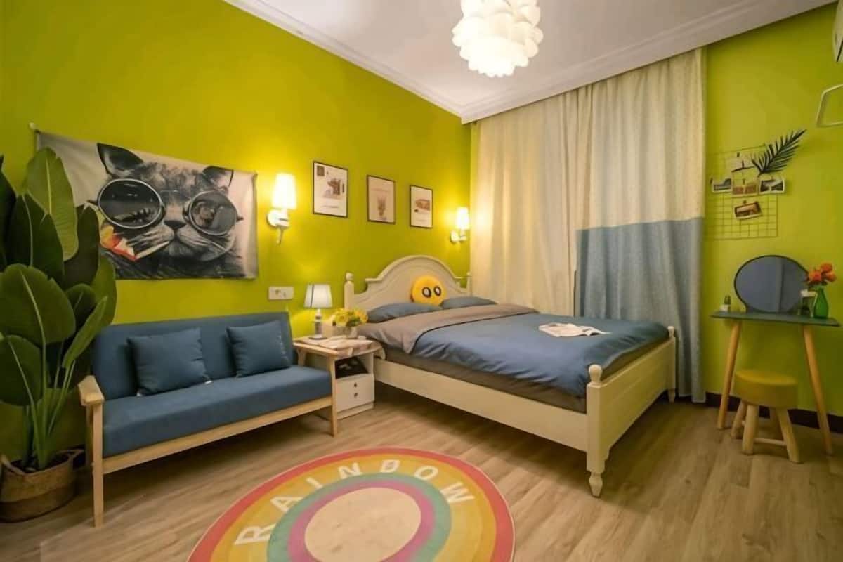 A room with a bed, a sofa, a desk, and a chair.