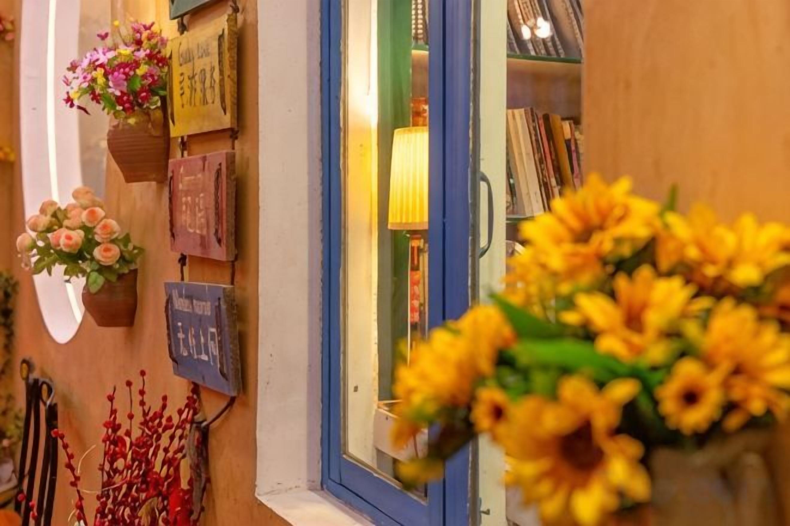 A storefront with a variety of items displayed outside, including flowers and signs.