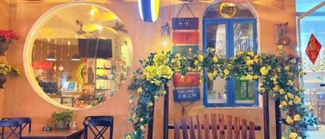 Un interior de restaurante con un espejo redondo, bancos de madera y un arco floral.
