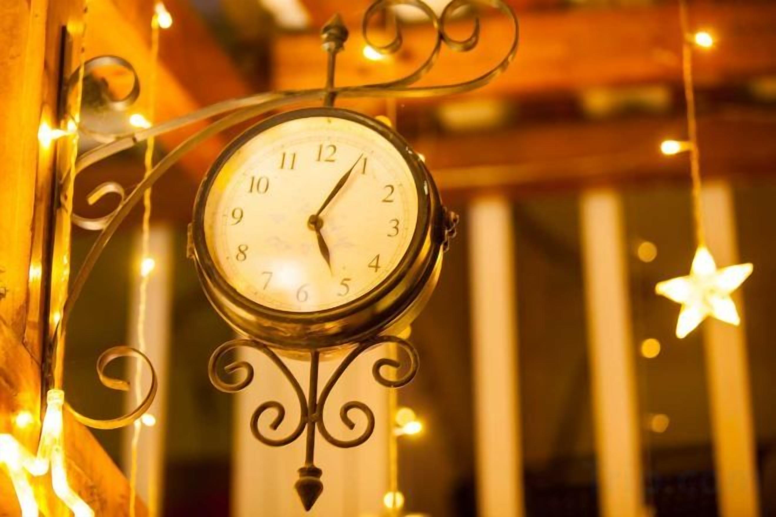 Un reloj de pared con un marco metálico decorativo y esfera blanca sencilla.