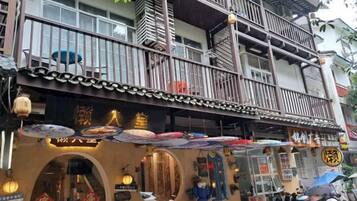 A traditional building with a balcony, multiple windows, and a storefront with umbrellas.