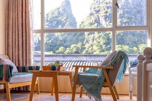 A room with a large window, a wooden table, a sofa, and a chair. - Yangshuo Lazy People's Hall Inn (West Street Lijiang Branch) (Yangshuo)