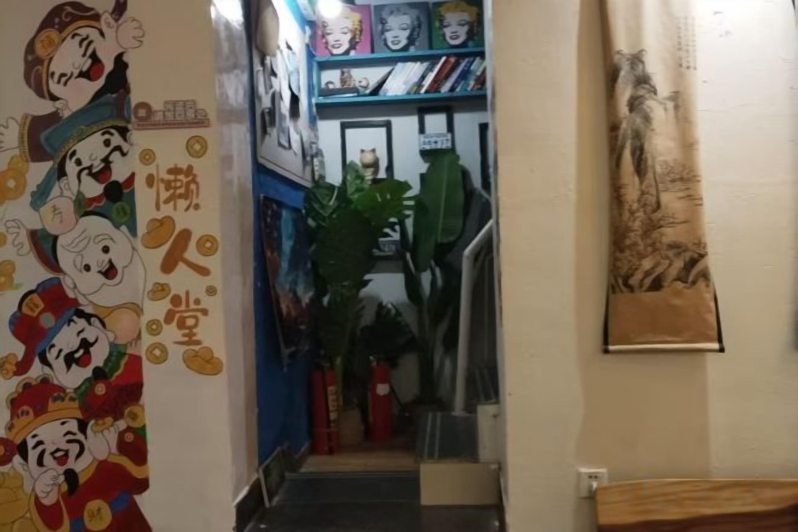 A narrow hallway with a staircase, a wall with cartoon characters, and a plant.
