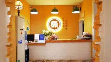 A hotel reception area with a counter, a computer, and a wall-mounted sign.